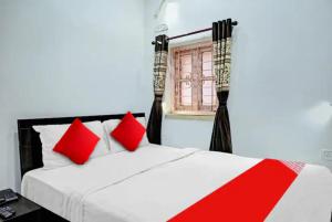 una camera da letto con un letto con cuscini rossi e una finestra di Hotel Laxmi Guest House Jadavpur - Excellent Service a Calcutta