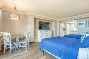 1 dormitorio con 1 cama azul, mesa y sillas en Great 1st floor unit that looks right out onto the beach with direct access, en Myrtle Beach