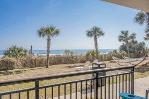 Una vista de una playa con palmeras y una hamaca. en Great 1st floor unit that looks right out onto the beach with direct access, en Myrtle Beach