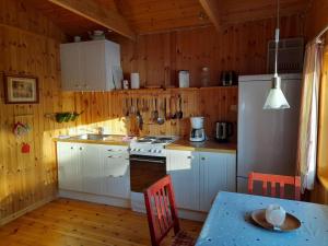 a kitchen with white cabinets and a refrigerator and a table at Haus Rangen in Brograngen