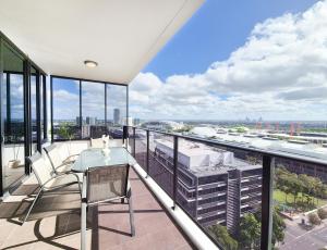 uma varanda com uma mesa e cadeiras num edifício em Holiday Style 2 BRStudy Apartment in Olympic Park em Sydney