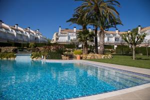 uma piscina num resort com palmeiras e edifícios em Casa 7 Parc Sant Ramon descanso y armonía em Platja d'Aro