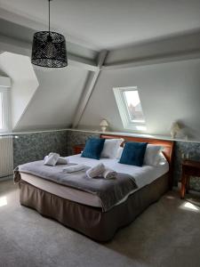 a bedroom with a large bed with blue pillows at La Granitiere Maison de Charme in Saint-Vaast-la-Hougue