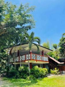a house with a red and white deck and trees at Daily Bread Organic Farm & Resort in Bustos