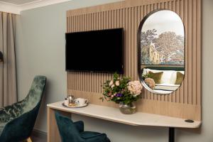 een kamer met een bureau met een spiegel en een televisie bij Menlo Park Hotel in Galway