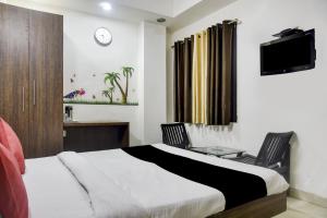 een slaapkamer met een bed, een bureau en een televisie bij Collection O 81293 Hotel Aditya Palace in Bhopal