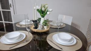 a dining room table with white plates and glasses at Comfort at Enchanted Dwellings in London