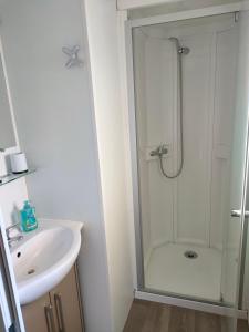 uma casa de banho branca com um chuveiro e um lavatório. em Mobil-home Siblu Les Rives de Condrieu em Condrieu