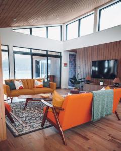 a living room with orange furniture and a flat screen tv at Lakeview Mid Century Luxury Cottage in Sainte-Adèle +47 photos