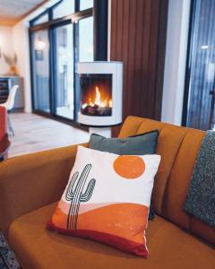 a pillow sitting on a couch with a fireplace at Lakeview Mid Century Luxury Cottage in Sainte-Adèle