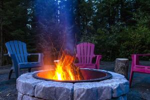 three chairs sitting around a fire pit in a yard at Le Mésangeai in Lac-Superieur