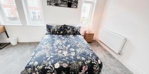 a bedroom with a bed with a floral bedspread at Spacious Room in Modern House near Nottingham in Nottingham