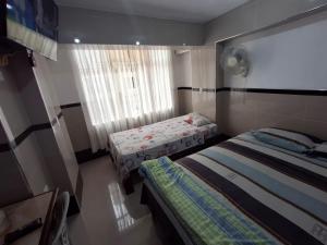 a small bedroom with two beds and a window at Hostal Jovita in Lima