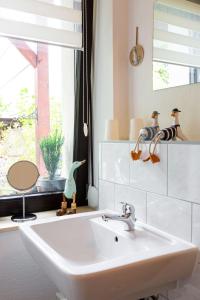 ein Bad mit einem weißen Waschbecken und einem Fenster in der Unterkunft Ferienwohnung am Auensee in Leipzig