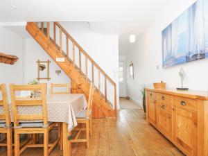 a dining room with a table and a staircase at Lowena Cottage in Looe