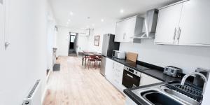 a kitchen with white cabinets and a wooden floor at Spacious Room in Modern House near Nottingham in Nottingham