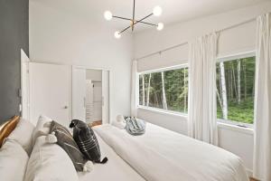 a white bedroom with a couch and a large window at Chalet La Colline in Labelle
