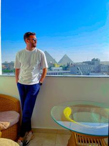 Un uomo in piedi in una stanza che guarda fuori dalla finestra di The Muse Pyramids INN a Il Cairo
