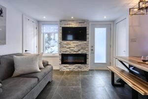 Le mini chalet في Sainte Anne des Lacs: غرفة معيشة مع أريكة ومدفأة