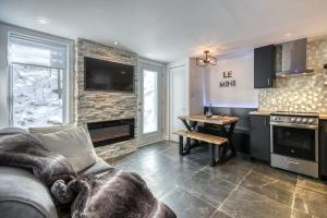 Le mini chalet في Sainte Anne des Lacs: غرفة معيشة مع أريكة ومطبخ
