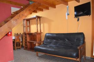 a black leather couch in a room with a tv at Cabañas Buena Vista Rosi in San Carlos de Bariloche