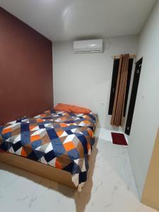 a bedroom with a bed with a colorful comforter at Losmen cempaka in Sibengkok