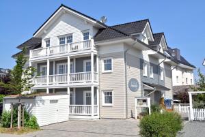 ein großes weißes Haus mit einem weißen Zaun in der Unterkunft Villa Somersby Ferienwohnung Nr 05 in Niendorf