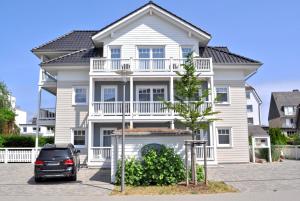 ein weißes Haus mit einem davor geparkt in der Unterkunft Villa Somersby Ferienwohnung Nr 05 in Niendorf