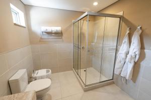 a bathroom with a toilet and a glass shower at Faro Norte Suites in Asunción