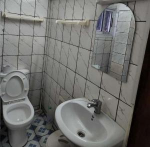 La salle de bains est pourvue de toilettes, d'un lavabo et d'un miroir. dans l'établissement Chambre Meublée à Douala, Bonapriso - Armée del'air, à Douala