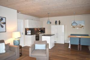 ein Wohnzimmer mit einem Sofa und einem Tisch sowie eine Küche in der Unterkunft Villa Somersby Ferienwohnung Nr 02 in Niendorf