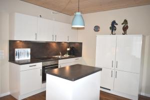 eine Küche mit weißen Schränken und einer schwarzen Arbeitsplatte in der Unterkunft Villa Somersby Ferienwohnung Nr 02 in Niendorf