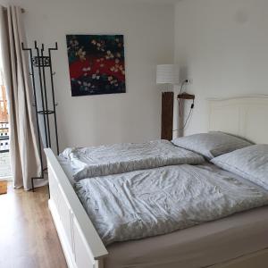 a bed in a white bedroom with a painting on the wall at Ferienwohnung an der Trave in Bad Segeberg