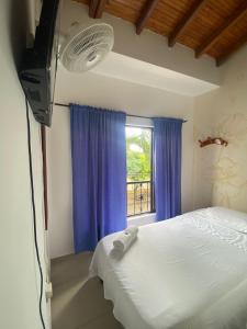 a bedroom with a bed and a tv and a window at HOTEL LAS PALMAS in La Virginia