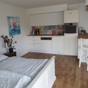 a kitchen with white cabinets and a bed in a room at Ferienwohnung an der Trave in Bad Segeberg