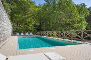 einen Pool mit Stühlen, einem Zaun und Bäumen in der Unterkunft Villa Mambrini in Sorrent