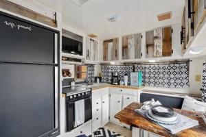 a small kitchen with white cabinets and a wooden table at #StayinMyDistrict Twin Falls Backyard Glamper in Twin Falls