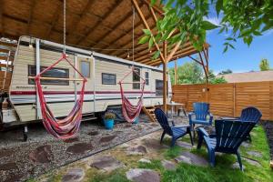 an rv with chairs and a hammock in a yard at #StayinMyDistrict Twin Falls Backyard Glamper in Twin Falls