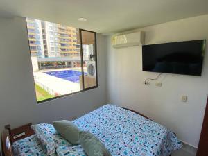 um quarto com uma cama, uma televisão e uma janela em Hermoso Apto en Ricaurte con piscina em Ricaurte