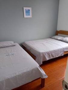dos camas sentadas una al lado de la otra en una habitación en Habitaciones Matrimoniales en Playa Pulpos HOSPEDAJE DELFINES HOUSE, en Lurín