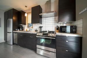 una cocina con electrodomésticos de acero inoxidable y armarios negros en #StayInMyDistrict Buckman Bright Spacious Townhome, en Portland