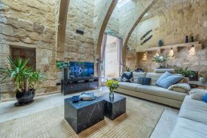 ein Wohnzimmer mit einem Sofa und einem TV in einer Steinwand in der Unterkunft Zaffir Retreat in Żebbuġ