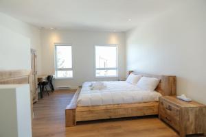 sypialnia z drewnianym łóżkiem i 2 oknami w obiekcie Chalet Élios w mieście Brownsburg
