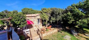 a house with chairs and an umbrella and trees at La Bergerie de Pauline - Bord de mer, vue unique in Pianottoli-Caldarello