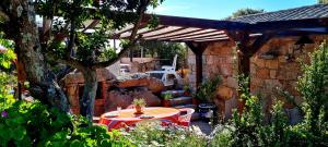 a patio with a table and a wooden pergola at La Bergerie de Pauline - Bord de mer, vue unique in Pianottoli-Caldarello +29 photos