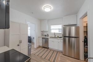 a kitchen with white cabinets and a stainless steel refrigerator at #StayinMyDistrict Goldfinch Cottage Coos Bay in Coos Bay