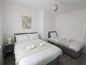 Duas camas num pequeno quarto com paredes brancas em Alexander Apartments Dudley em Seaton Burn