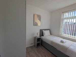 a white bedroom with a bed and a window at Alexander Apartments Dudley in Seaton Burn