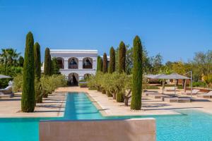 a villa with a swimming pool and cyprus trees at Ca Na Xica - Hotel & Spa in Sant Miquel de Balansat