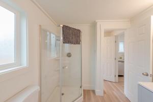 a white bathroom with a shower with a glass door at #StayInMyDistrict Indigo Cottage Coos Bay in Coos Bay